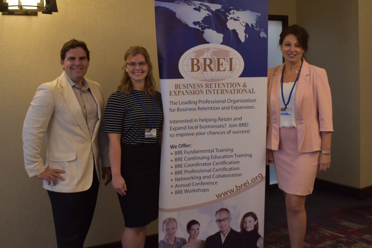 members posing next to BREI banner
